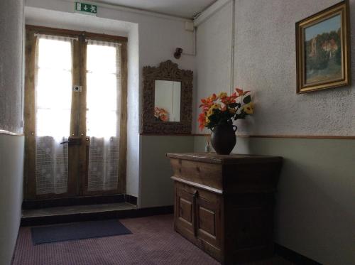a room with a vase of flowers on a wooden dresser at Hotel Restaurant de la Poste in Aullène