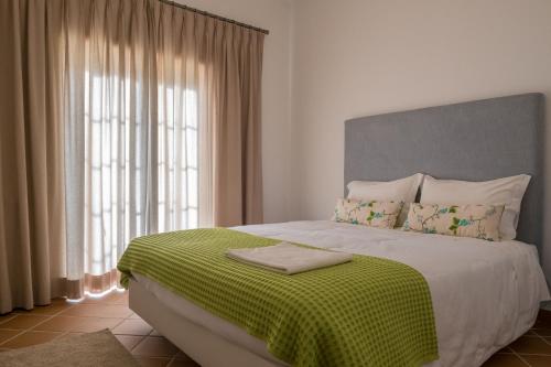 a bedroom with a large bed with a green blanket at T3 Vila dos Principes in Amoreira