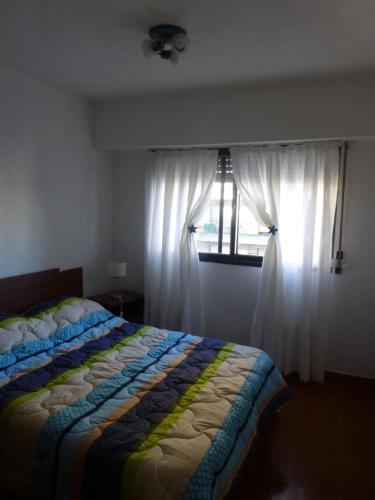 a bedroom with a bed and a window with white curtains at Como en Casa in Rosario