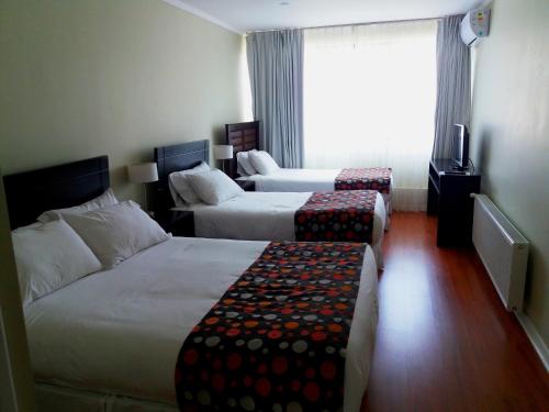a hotel room with two beds and a window at Hotel Del Rio in Constitución