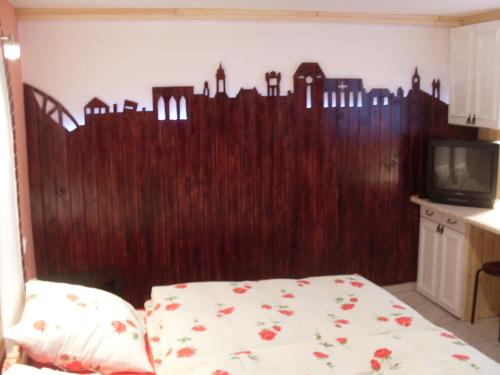 a bedroom with a wooden wall with a bed and a tv at Apartament na Wrzosach in Toruń