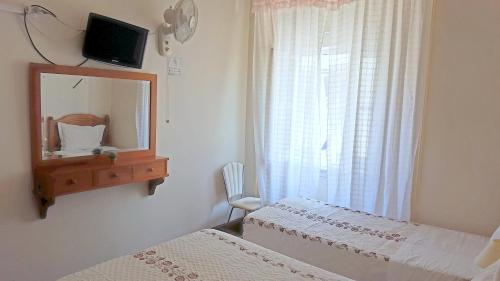 a bedroom with two beds and a mirror and a window at Pensão Prata in Lisbon