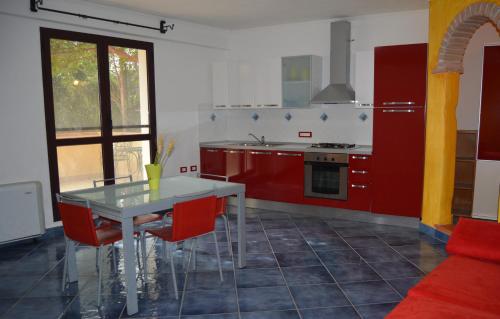 a kitchen with red cabinets and a white table at Melalidone in Orosei