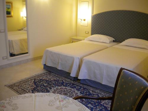 a hotel room with two beds and a mirror at Villaggio San Giovanni in San Giorgio Ionico