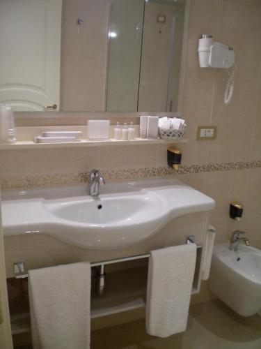 a bathroom with a sink and a mirror and a toilet at Villaggio San Giovanni in San Giorgio Ionico