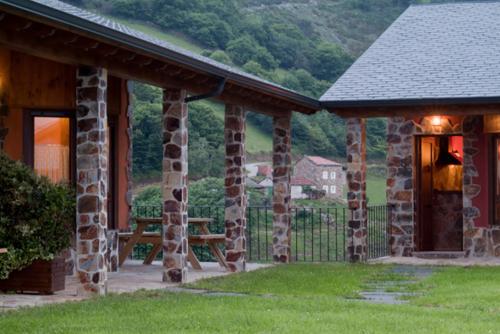 a stone building with a bench in the yard at Apartamentos Rurales El Fresnu in Silvamayor