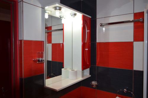 La salle de bains est pourvue d'un miroir et de carreaux rouges et noirs. dans l'établissement Hotel Yax, à Câmpeni