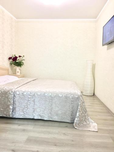 a white bedroom with a bed and a vase of flowers at Vilari Odessa in Odesa
