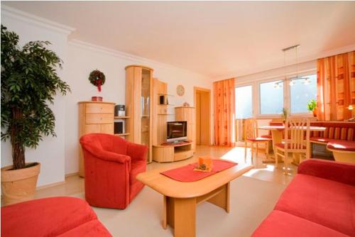 a living room with a red couch and a table at Appartements Kristall in Abtenau