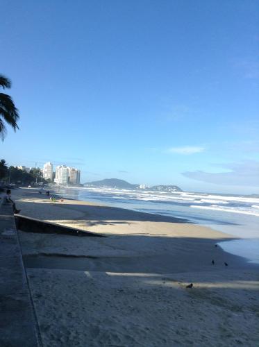 uma praia com o oceano e edifícios ao fundo em Cello´s Apartamento no Guarujá