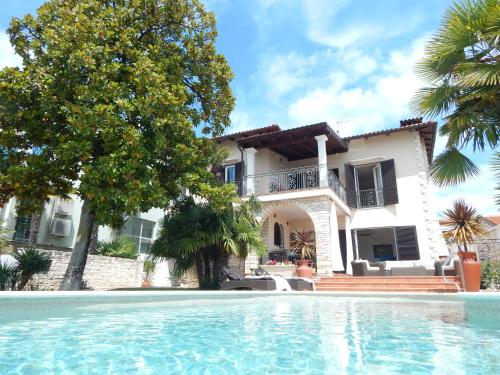 a villa with a swimming pool in front of a house at Villa Magnolia Umag in Umag