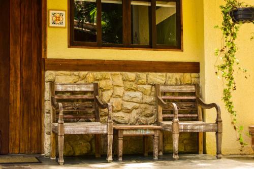 two wooden benches sitting in front of a building at Espaço CurAmar - Praia de Itamambuca in Ubatuba