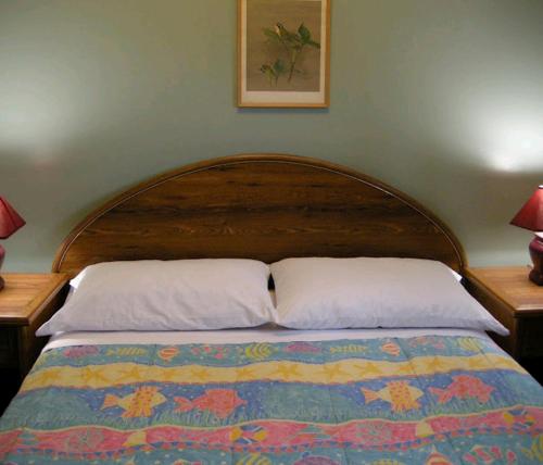 uma cama com uma cabeceira em madeira com 2 almofadas em Birch Haven by the Beach em Wasaga Beach