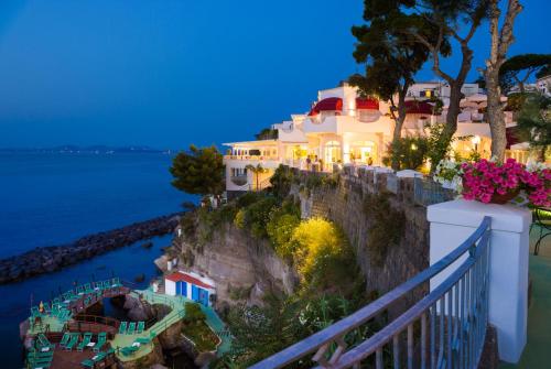 a house on a cliff near the water at night at Hotel La Madonnina in Ischia