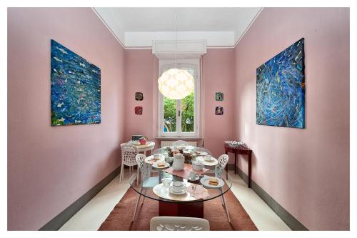 una sala da pranzo con pareti rosa e tavolo in vetro di Villa Italy a Marina di Pietrasanta