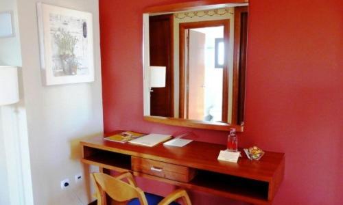 Habitación roja con escritorio de madera y espejo. en Hotel Restaurante El Tollo, en Utiel