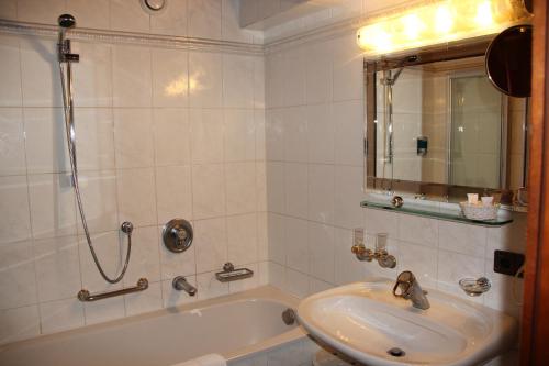 a bathroom with a sink and a tub with a mirror at Hotel Tyrolis in Zirl