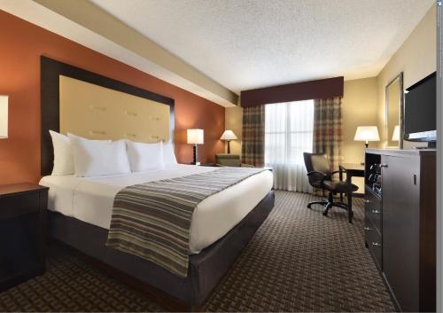 Country Inn & Suites by Radisson, Evansville, IN في إيفانسفيل: غرفة الفندق بسرير كبير ومكتب