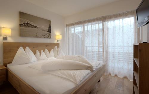 a white bed with white pillows and a window at Appartements Kirchenwirt in Kirchberg in Tirol