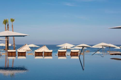 a beach with chairs and umbrellas in the water at Krystal Grand Los Cabos - All Inclusive in San José del Cabo