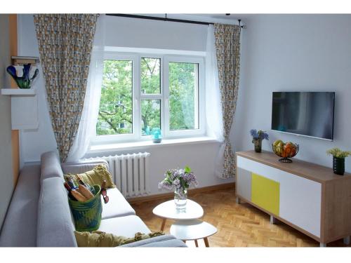 a living room with a couch and a tv and a window at Nowolipie Warsaw Apartment in Warsaw