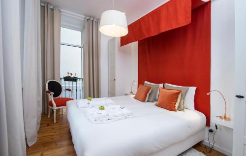 a bedroom with a white bed with a red wall at Lisbon Dreams Estrela Suites in Lisbon