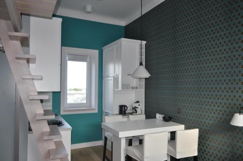 a kitchen with green walls and a white table and chairs at Apartament na Wilczej in Warsaw