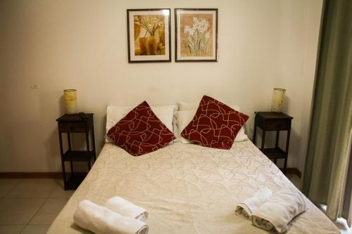 Un dormitorio con una cama con almohadas rojas. en Edymar en Puerto Madryn