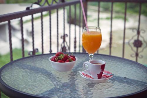 a glass of orange juice and a cup of fruit on a table at Motel Vila Bijela in Konjic