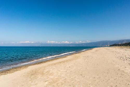 a sandy beach with water and mountains in the background at Case Panoramiche sul Lago in Messina