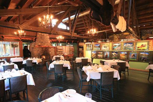 un restaurante con mesas y sillas blancas en una habitación en Sunwapta Falls Rocky Mountain Lodge, en Jasper