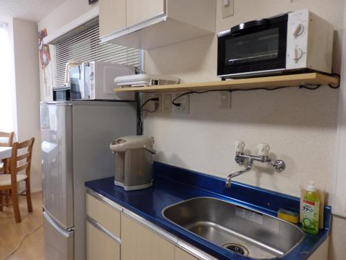 a kitchen with a sink and a microwave and a refrigerator at Backpacker's Mini House in Tokyo