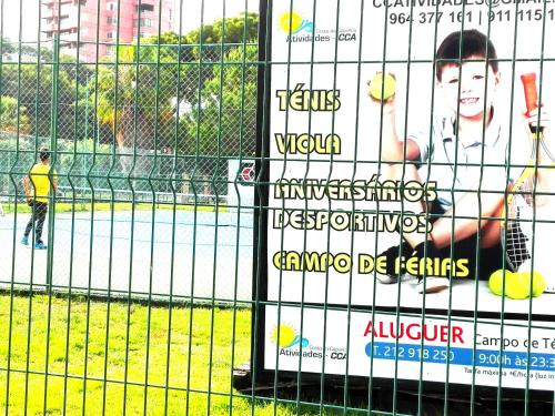 a fence with posters on it next to a tennis court at Lisbon Coast Flat in Quinta de Santo António