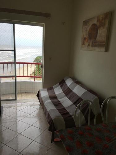 ein Schlafzimmer mit Bett und Blick auf einen Balkon in der Unterkunft Apartamento pé na areia in Itanhaém
