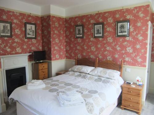 a bedroom with a large bed with red wallpaper at Grange Farm House in Felixstowe