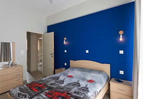 レティムノ・タウンにあるCentral Luxury Apartmentの青い壁のベッドルーム1室、ベッド1台が備わります。