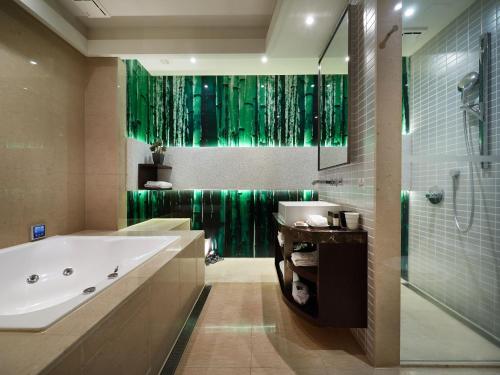 a bathroom with a tub and a green shower curtain at The Tango Hotel Taipei XinYi in Taipei