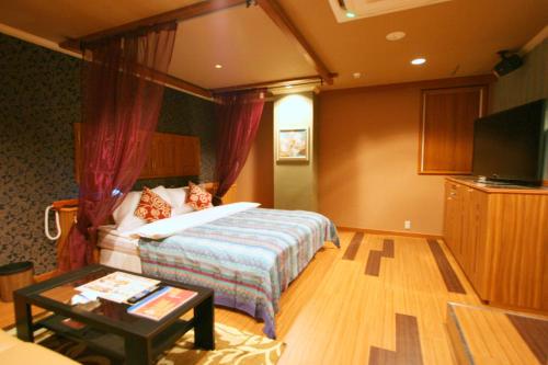 um quarto de hotel com uma cama e uma mesa de centro em Aura Kanku (Adult Only) em Sennan