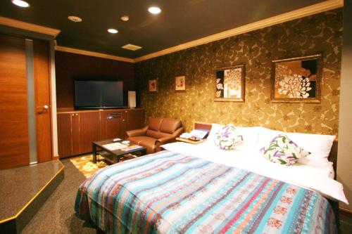 a bedroom with a bed and a couch and a television at Aura Kanku (Adult Only) in Sennan