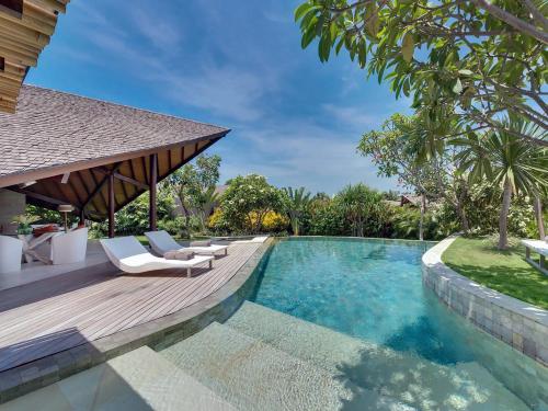 a swimming pool with a deck and chairs next to a house at The Layar - Designer Villas and Spa, CHSE Certified in Seminyak