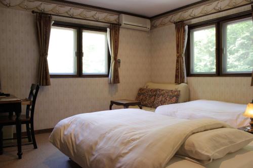 a bedroom with two beds and a desk and two windows at Lumiere in Fujikawaguchiko