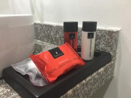 a shelf with two bottles ofodorizers and a bag at Hangar Inn Guadalajara Aeropuerto in Guadalajara