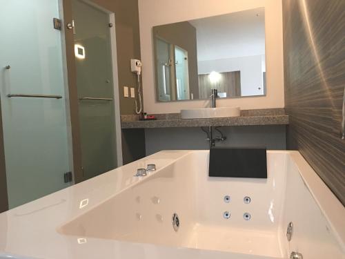 a bathroom with a large white tub and a sink at Hangar Inn Guadalajara Aeropuerto in Guadalajara