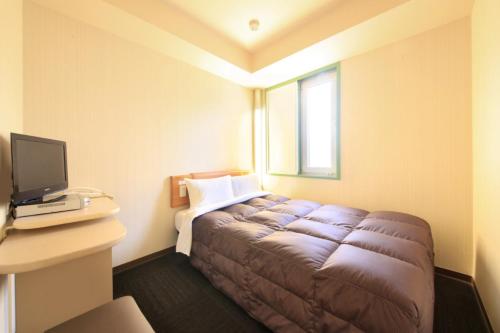 
a bedroom with a bed, desk, and television at R&B Hotel Sendai Hirosedori Ekimae in Sendai
