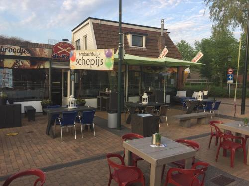 un restaurante con mesas y sillas frente a un edificio en Appartement De Kaai, en Sint Annaparochie