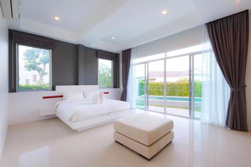 a bedroom with a white bed and a large window at Hideaway Pool Villa S126 in Suan Son