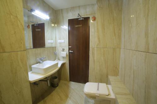 a bathroom with a sink and a toilet and a mirror at Hotel Grand Pragati in Surat