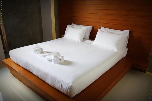 a large white bed with two cups and saucers on it at Merdelong Hotel in Phatthalung