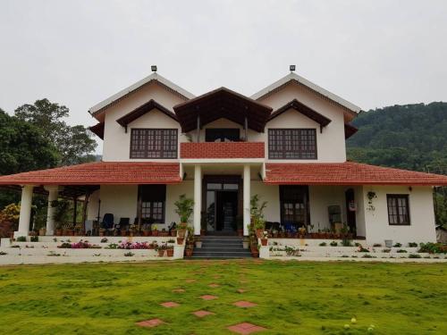 a house with a lawn in front of it at Abiyal Mountain Stay in Madikeri