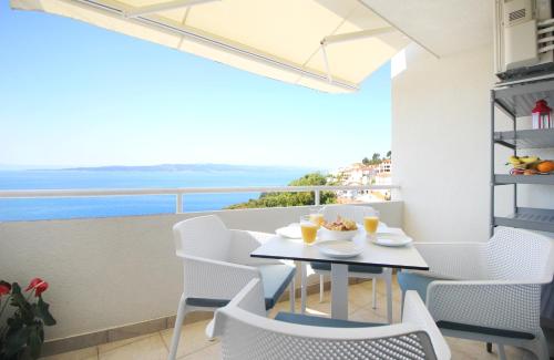 un tavolo e sedie su un balcone con vista sull'oceano di New Gallery Apartment with Beautiful View a Baška Voda
